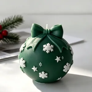 Detail van een groene kerstbal geurkaars versierd met witte sneeuwvlokken en sterren
