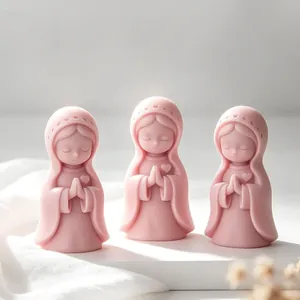 Close-up of three pink praying girl figurines made from silicone candle molds