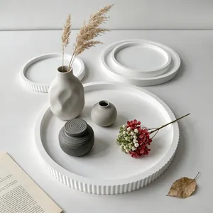 Detailed view of white fluted round tray with minimalist decorative vases and flowers