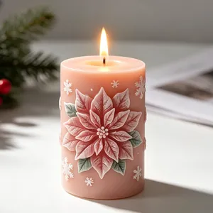Detail view of lit pink Christmas pillar candle with 3D embossed poinsettia flower