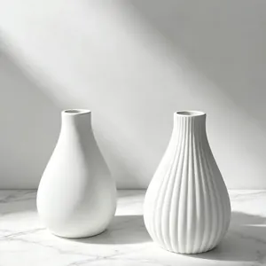 Close-up detail view of smooth and striped white minimalist vases on a marble surface