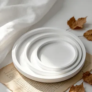 Detail of white round nesting trays set on vintage paper and dried leaves