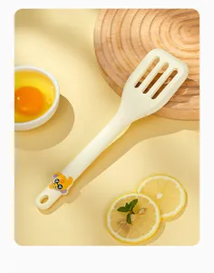 Close-up detail view of cream silicone slotted spatula with a cute cartoon character
