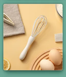 Macro view of a white silicone whisk with kitchen props including eggs and flour