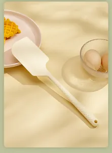 Macro view of cream silicone spatula with textured handle in a kitchen setting