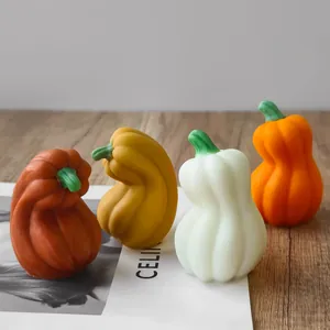 Four artistic multi-colored Halloween pumpkin candles displayed on a rustic wooden table.