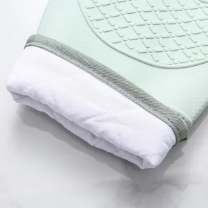 Detailopname van een lichtgroene siliconen ovenwant met dikke witte katoenen manchet.