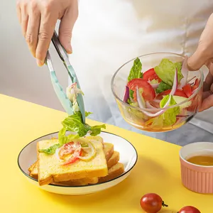 Silicone food tongs used to serve fresh salad on toast in a bright kitchen setting