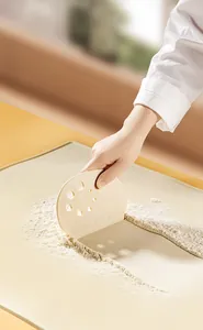 Rascador de masa de PP beige con escala en cm usado en un tapete de cocina a juego