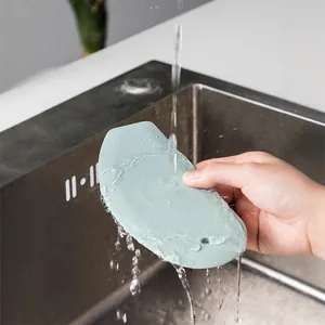 Mint green silicone dough scraper and baking spatula being rinsed under water in a sink