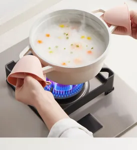 Pink heat-resistant silicone pot handle clips shown in a real kitchen cooking scene