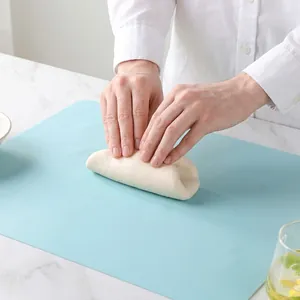 Large light blue thick silicone kneading mat for baking on a white marble countertop