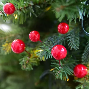 Nahaufnahme künstlicher roter Beeren an einem Weihnachtsbaum mit warmen Lichtern