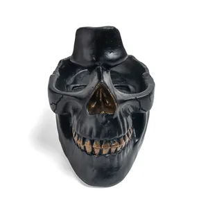 Detailed view of a black resin skull sculpture with gold-toned teeth accents