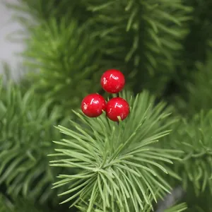 Detailansicht glänzender roter Kunstbeeren eingebettet in grüne Weihnachtskieferzweige