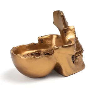 Close-up detail of a golden resin skull sculpture designed as a creative eyeglass and key holder.