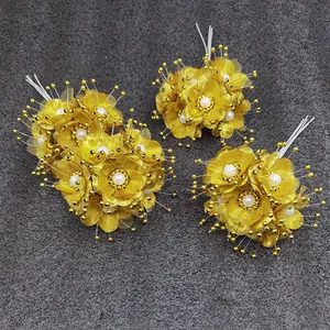 Makro-Detail von drei goldenen Mini-Stoffblumen mit Kunstperlen und goldfarbenen Perlen