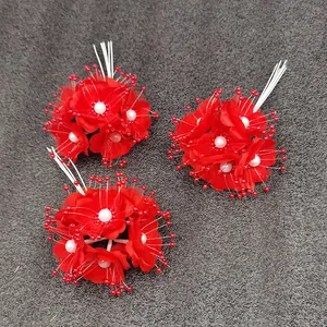Detail von roten künstlichen Mini-Sträußen mit weißen Perlen für den Brautschmuck.