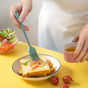 Professional green silicone basting brush applying honey or oil to toast slices.