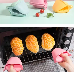 Hands using pink silicone heat resistant pinch grips to pull out an oven rack