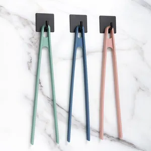 Set of three heat-resistant colorful silicone food tongs hanging on modern wall hooks