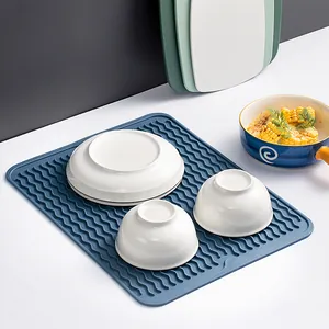 Escurridor de silicona azul con diseño ondulado resistente al calor para mesa de cocina.