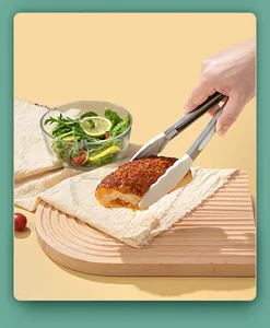 Close-up of food-grade silicone kitchen tongs picking up bread over a wooden board
