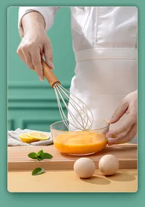 Silicone whisk with wooden handle beating eggs in a glass bowl, macro kitchen view.