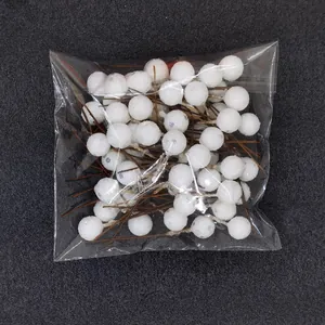 Detailed view of white glitter Christmas berries in clear plastic packaging.