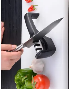 Detail of manual 3-stage kitchen knife sharpener in use with vegetables on cutting board