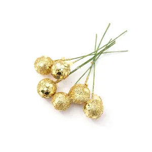 Macro detail of golden glittery berries on thin green wire stems for festive DIY decor.