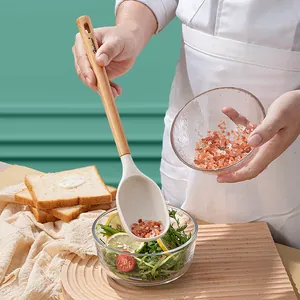White silicone cooking spoon with ergonomic wooden handle used for salad seasoning and salt