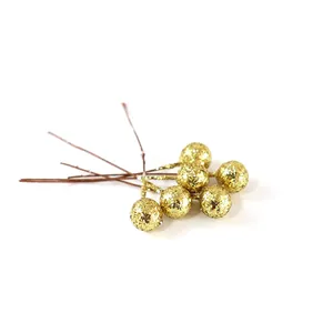Close-up of artificial gold glitter berries on wire stems for festive DIY crafts