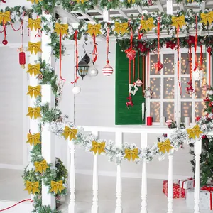 Festliche goldene Glitzer-Weihnachtsschleifen auf verschneiter Girlande am Balkon