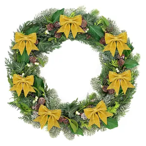 Detailansicht goldener Glitzer-Weihnachtsschleifen auf einem dekorativen Tannenkranz