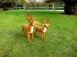 Paar lebensechte Weihnachts-Rentierfiguren auf einem üppigen, sonnigen grünen Rasen