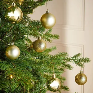 Detailed view of shiny and glittery gold Christmas baubles hanging on a pine tree