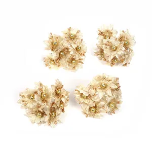 Detailansicht von vier Bündeln goldener Stoff-Kamelienblüten für DIY-Haarschmuck
