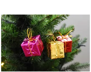 Close-up of colorful metallic mini gift box ornaments hanging on a green Christmas tree.