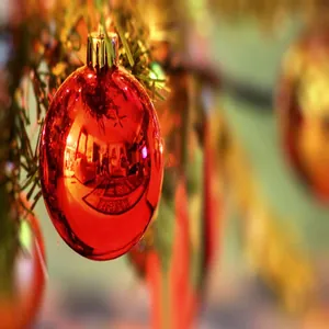 Nahaufnahme einer glänzenden roten Weihnachtskugel an einem Baum mit warmer Bokeh-Beleuchtung