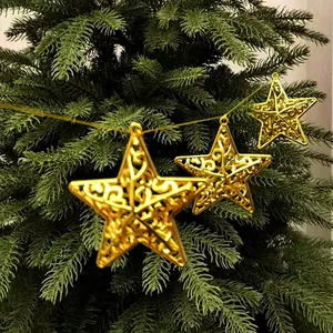 Detailed view of hollow gold star ornaments hanging on a green Christmas tree