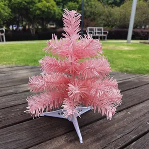 Detailansicht eines mini rosa Weihnachtsbaums mit weißem Kunststoffständer auf Holz.