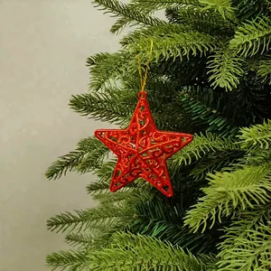 Detailed view of a red hollow star Christmas tree ornament on a green pine branch