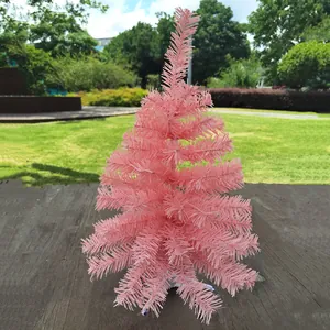 Rosa Mini-Weihnachtsbaum für Feiertagsdeko auf einem Holztisch im Freien