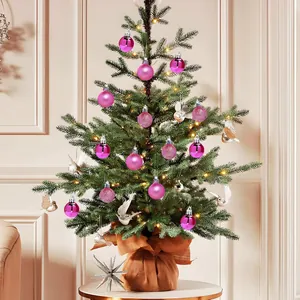 Close-up detail of pink Christmas ball ornaments hanging on a small pine tree for decoration