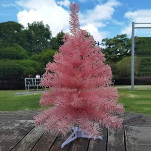 Künstlicher Mini-Weihnachtsbaum in Kirschrosa auf einem rustikalen Holztisch im Freien