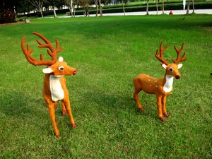 Detailansicht von zwei realistischen braunen Weihnachts-Rentier-Figuren auf Rasen