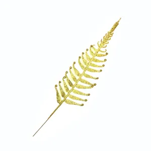 Close-up detail of a golden glitter fern leaf branch for Christmas tree decoration
