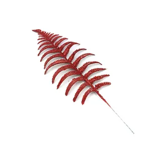 Close-up of a vibrant red glitter artificial fern leaf for festive Christmas tree decoration