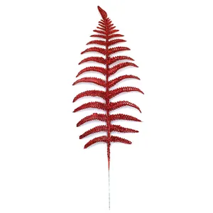 Detailed macro view of red glitter artificial fern leaf for Christmas tree decor.